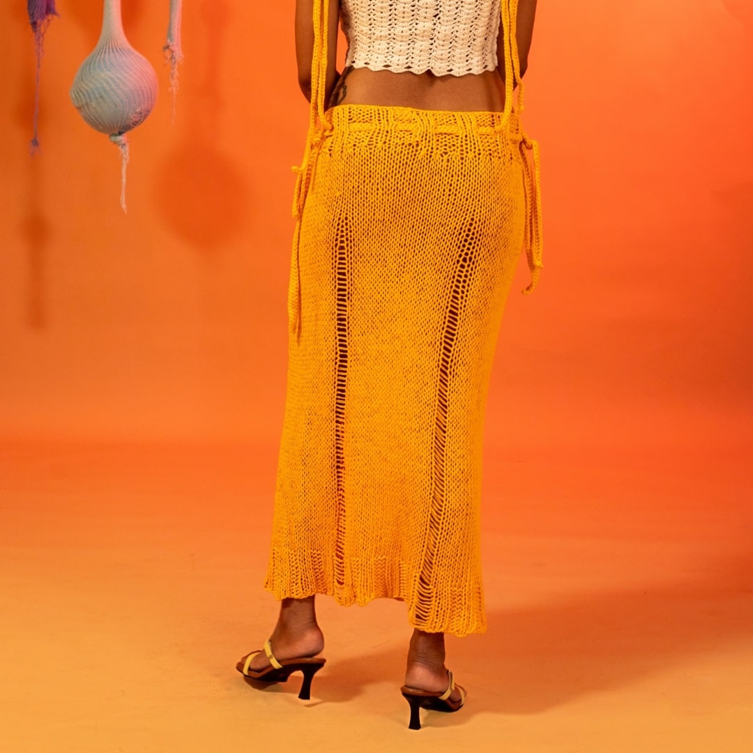 Back view of the Citrus knit skirt, featuring its straight fit and playful open-knit pattern.