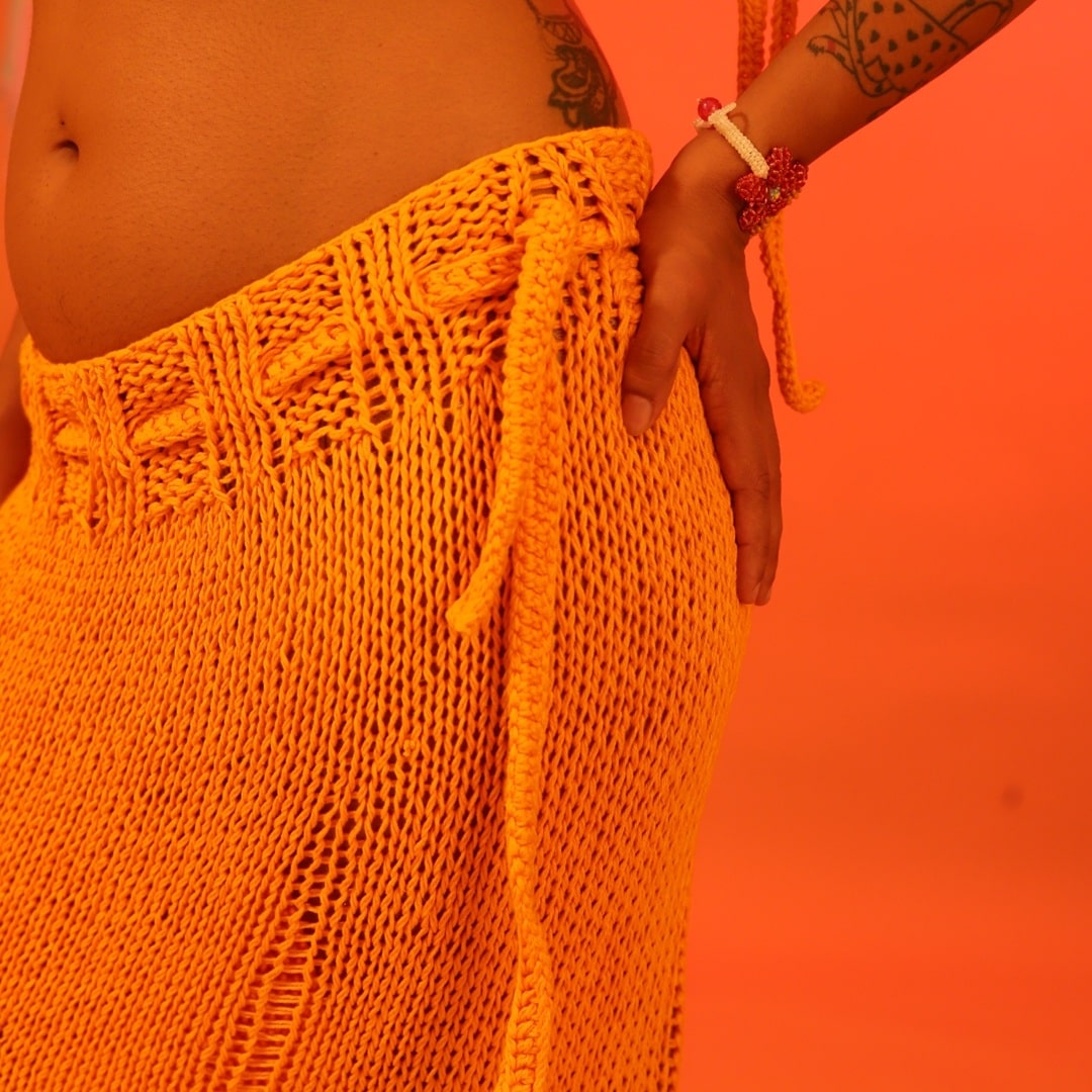 Side angle of the Citrus knit skirt, highlighting the waist ties and airy knit design.